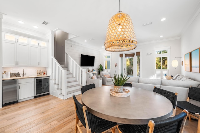 dining space with wet bar, visible vents, recessed lighting, beverage cooler, and light wood finished floors