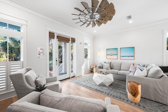 living room featuring crown molding, visible vents, plenty of natural light, and wood finished floors