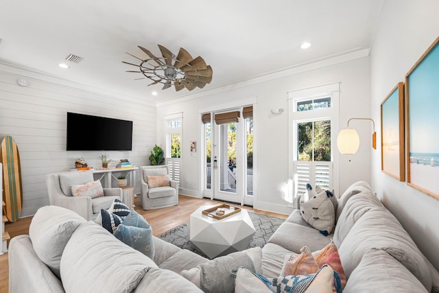 living area with light wood-style flooring, a ceiling fan, ornamental molding, and visible vents
