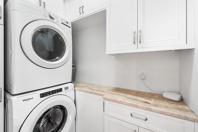 washroom with stacked washer and clothes dryer and cabinet space