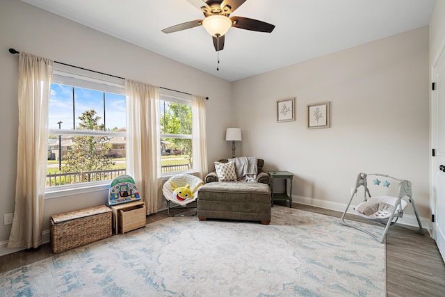 sitting room featuring a ceiling fan, baseboards, and wood finished floors