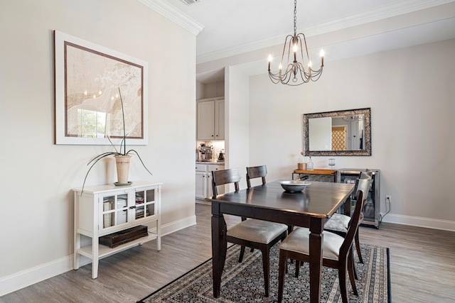 dining space with light wood-style floors, baseboards, ornamental molding, and a chandelier