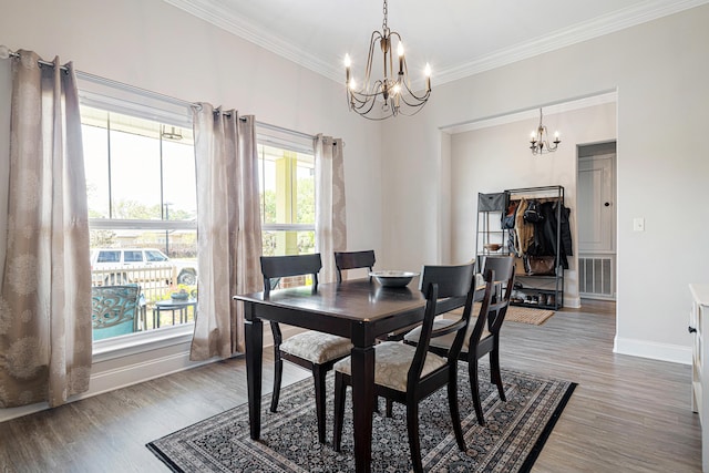 dining space featuring visible vents, ornamental molding, wood finished floors, baseboards, and a notable chandelier