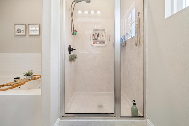 bathroom with baseboards, a jetted tub, and a stall shower