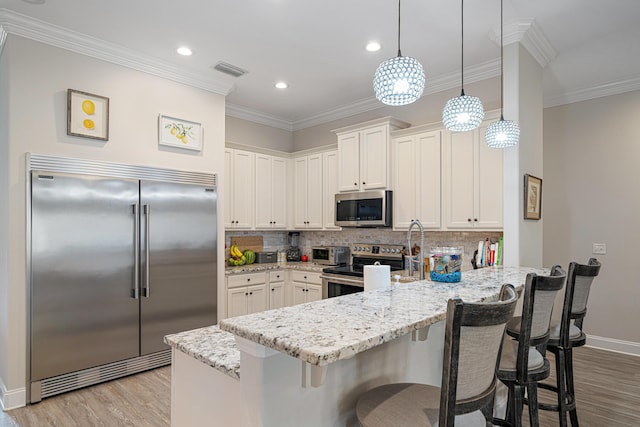 kitchen with visible vents, light wood-style flooring, a peninsula, and stainless steel appliances