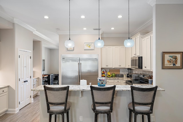 kitchen with decorative backsplash, a kitchen bar, light stone countertops, a peninsula, and stainless steel appliances