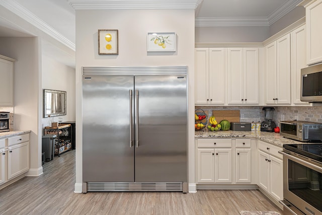 kitchen featuring crown molding, decorative backsplash, a toaster, light wood-type flooring, and appliances with stainless steel finishes