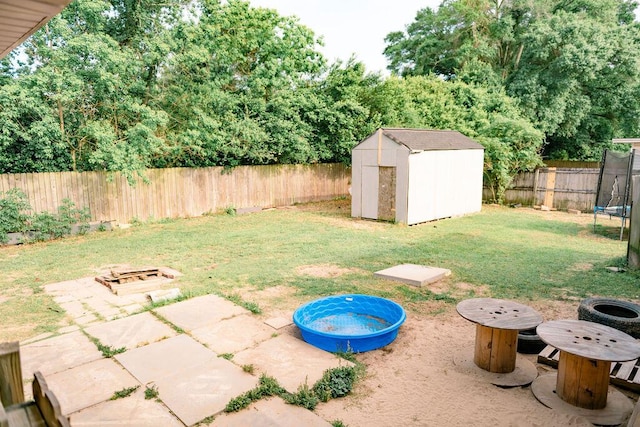 306 N 58th Ave, Pensacola, FL 32506 - view of yard with an outdoor fire pit, a trampoline, a fenced backyard, and a storage unit
