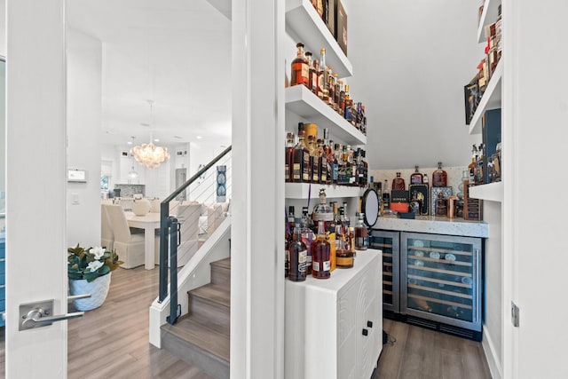 bar with wood finished floors, wine cooler, a dry bar, and stairway