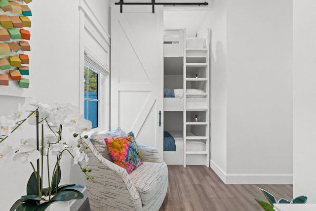sitting room featuring baseboards, a barn door, and wood finished floors