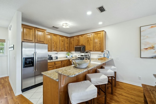 10 Mar A Lago Blvd # 14, Santa Rosa Beach, FL 32459 - kitchen with visible vents, brown cabinetry, light stone countertops, and stainless steel appliances