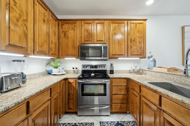 10 Mar A Lago Blvd # 14, Santa Rosa Beach, FL 32459 - kitchen with a sink, light tile patterned floors, stainless steel appliances, and brown cabinets