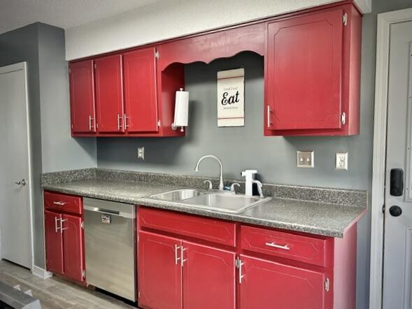 kitchen with red cabinetry, dishwasher, light wood-style flooring, and a sink