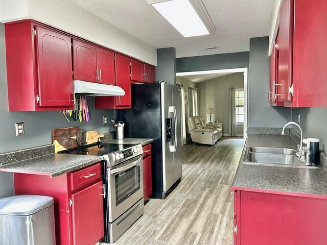 kitchen featuring red cabinets, a sink, appliances with stainless steel finishes, under cabinet range hood, and light wood finished floors