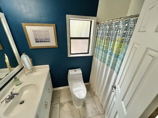 bathroom with tile patterned floors, a shower with shower curtain, toilet, and vanity