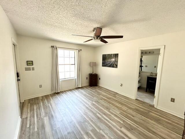 unfurnished room featuring a ceiling fan, baseboards, wood finished floors, and a textured ceiling