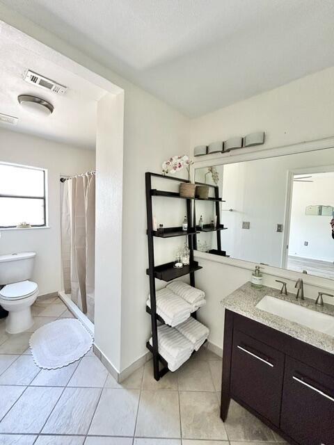 full bath with curtained shower, visible vents, toilet, vanity, and tile patterned flooring