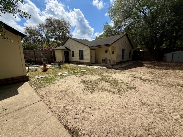 view of side of property featuring an outdoor structure, a shed, a patio, and fence