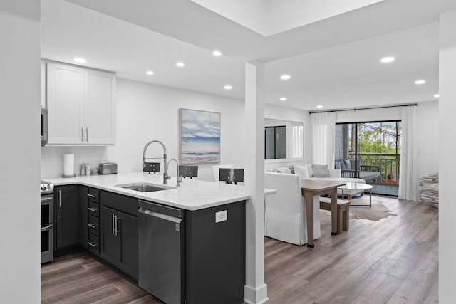 8980 Heron Walk Dr # 8980, Miramar Beach, FL 32550 - kitchen with wood finished floors, a sink, a peninsula, appliances with stainless steel finishes, and white cabinetry