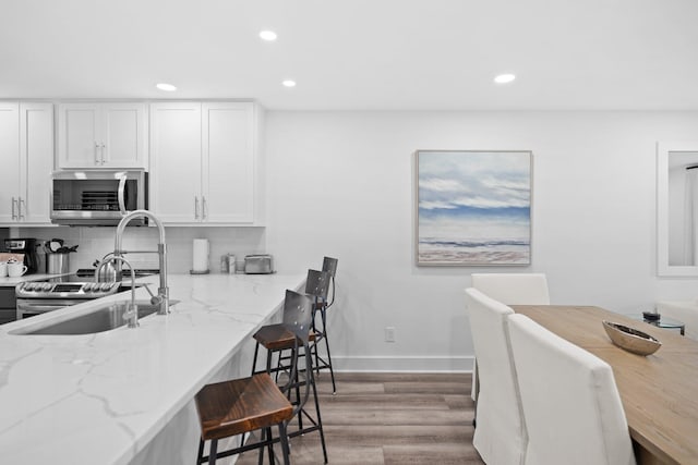 8980 Heron Walk Dr # 8980, Miramar Beach, FL 32550 - kitchen with light wood finished floors, stainless steel appliances, a kitchen breakfast bar, a sink, and recessed lighting