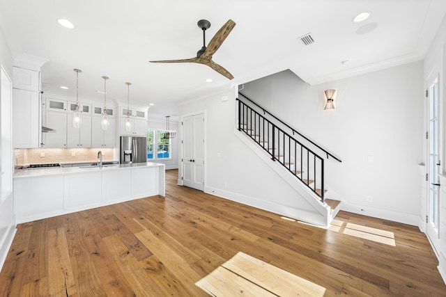 kitchen with glass insert cabinets, a sink, ornamental molding, and stainless steel fridge