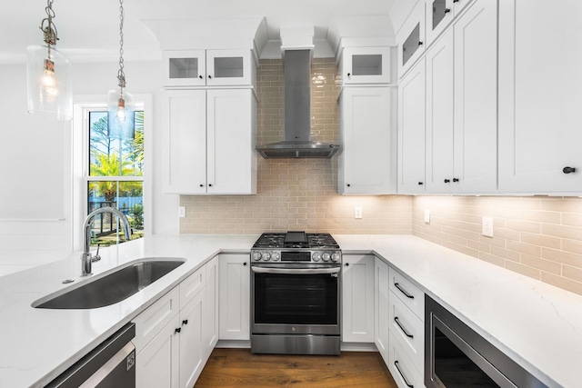 kitchen featuring dark wood finished floors, wall chimney range hood, a sink, stainless steel appliances, and backsplash