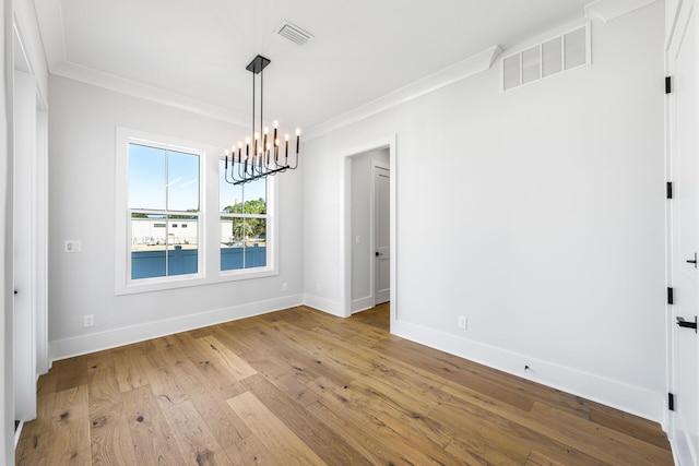 unfurnished dining area with a notable chandelier, baseboards, crown molding, visible vents, and wood-type flooring