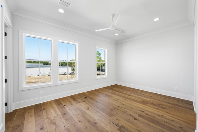 spare room featuring hardwood / wood-style floors, visible vents, baseboards, and ornamental molding