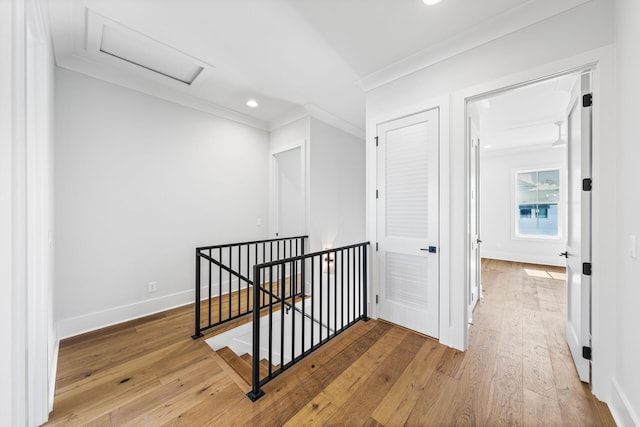 hall featuring baseboards, an upstairs landing, crown molding, attic access, and wood-type flooring
