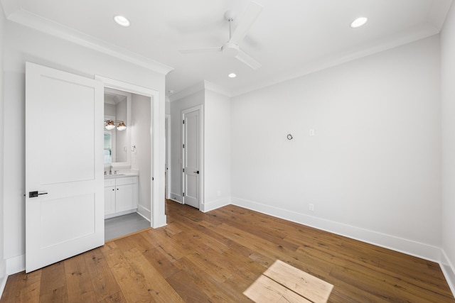 unfurnished bedroom with baseboards, recessed lighting, crown molding, wood-type flooring, and a sink
