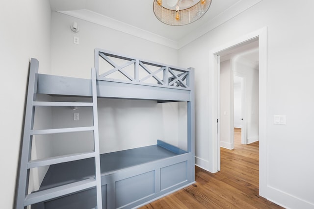 unfurnished bedroom with crown molding, baseboards, and wood finished floors