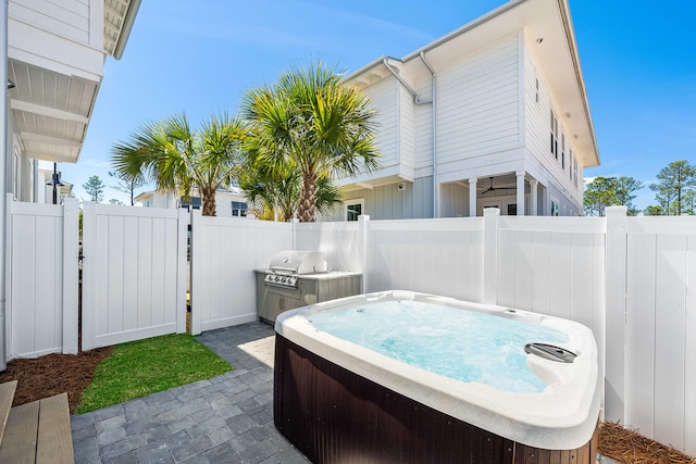 view of patio featuring grilling area, fence, a gate, and a hot tub
