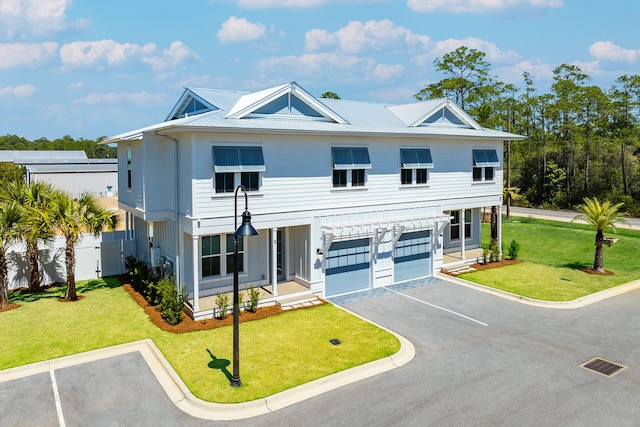 view of front facade featuring a front yard, an attached garage, fence, and metal roof