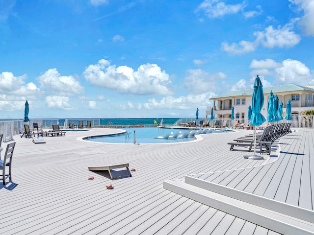 community pool with a deck with water view and fence