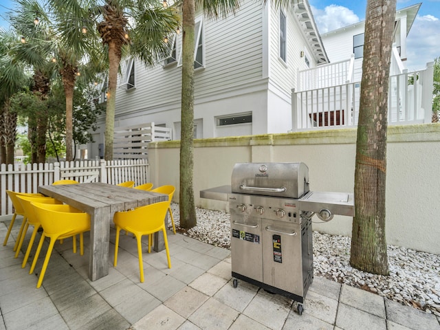 view of patio with grilling area, outdoor dining area, and fence