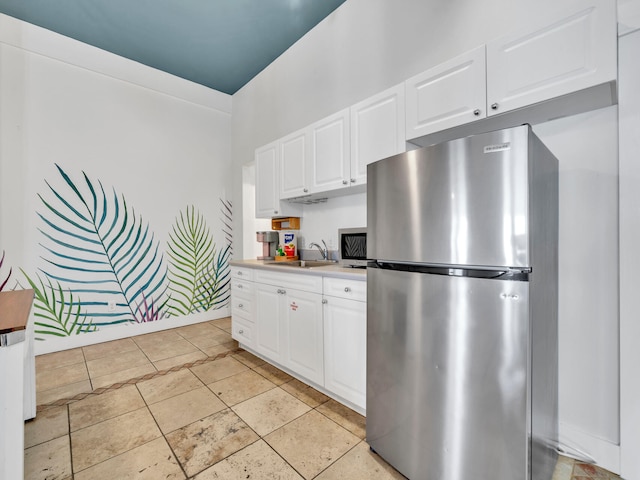 kitchen with white cabinetry, a sink, light countertops, and freestanding refrigerator
