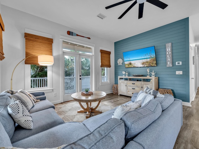 living area featuring an accent wall, baseboards, a ceiling fan, and visible vents
