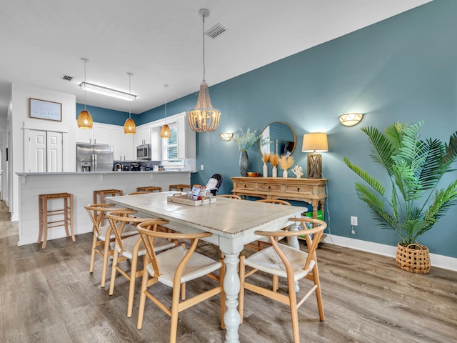 dining room with wood finished floors, visible vents, baseboards, and an inviting chandelier