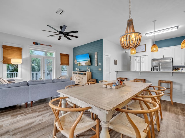 dining room featuring light wood-style floors, visible vents, and ceiling fan with notable chandelier
