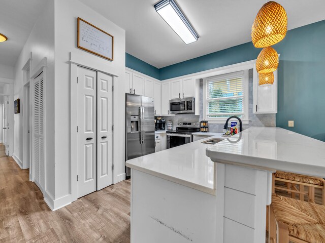 kitchen featuring white cabinets, stainless steel appliances, a peninsula, and a sink