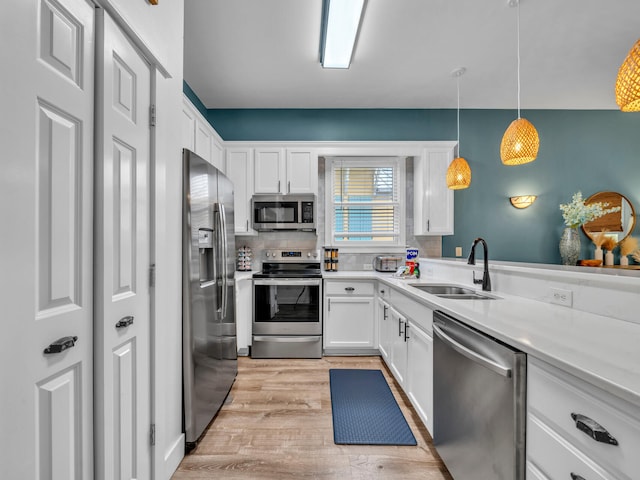 kitchen featuring light wood-style floors, appliances with stainless steel finishes, white cabinetry, and a sink