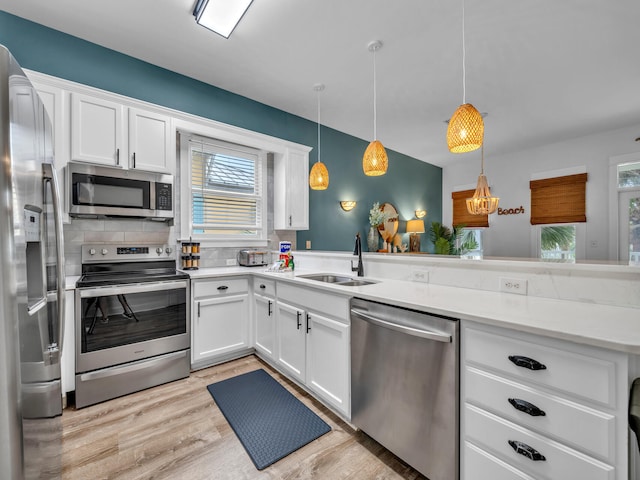 kitchen featuring a sink, light wood-style floors, white cabinetry, light countertops, and appliances with stainless steel finishes