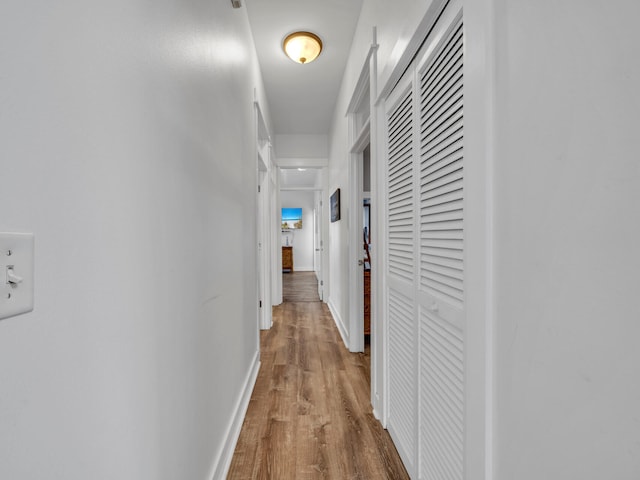 hallway featuring baseboards and wood finished floors