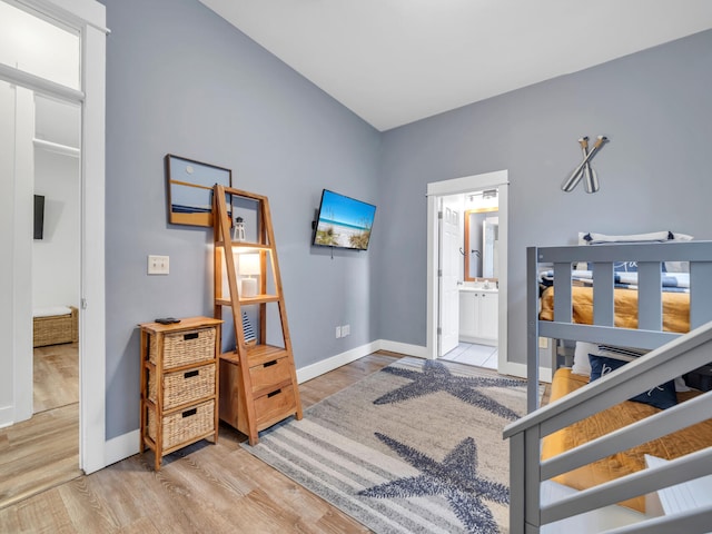 bedroom with ensuite bath, baseboards, and wood finished floors