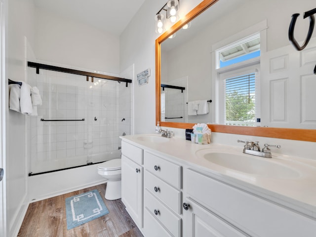 bathroom with toilet, wood finished floors, a sink, and double vanity