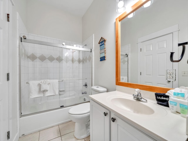 bathroom featuring tile patterned floors, vanity, combined bath / shower with glass door, and toilet