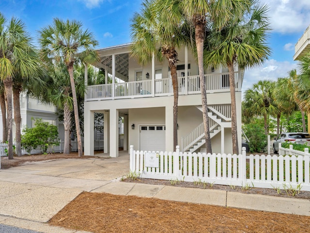 beach home featuring stucco siding, driveway, stairs, and a garage
