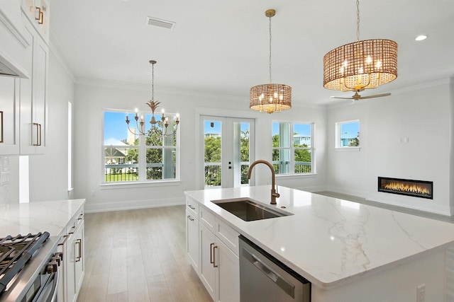 162 Casting Lake Rd, Miramar Beach, FL 32550 - kitchen with a chandelier, stainless steel dishwasher, light wood-style flooring, crown molding, and a glass covered fireplace