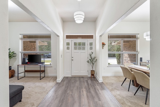 entryway with baseboards, wood finished floors, and carpet floors
