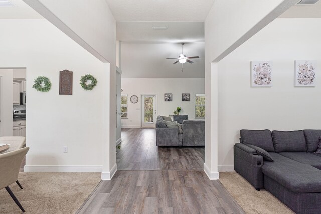 living area with baseboards, high vaulted ceiling, wood finished floors, and a ceiling fan